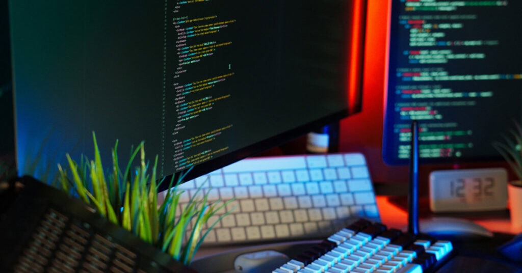 Modern workspace with computer screens displaying code and digital tools, symbolizing resources and technology for small business owners.