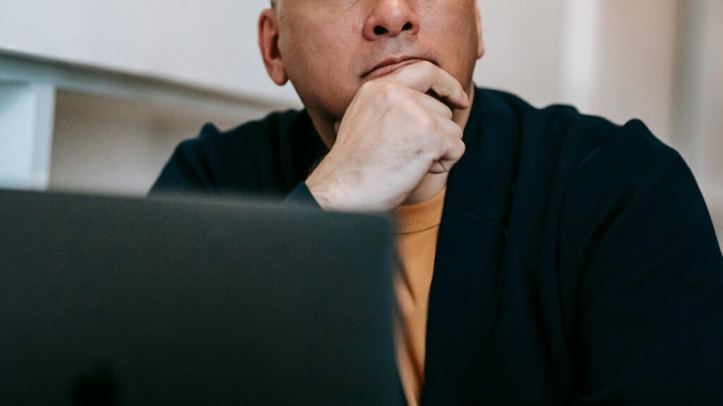 Small business owner thinking through ideas while working at a laptop, illustrating how AI supports everyday tasks.